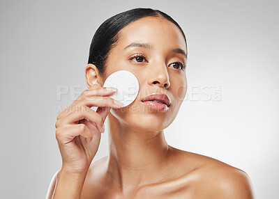 Buy stock photo Studio shot of an attractive young woman using a cotton pad on her face against a grey background