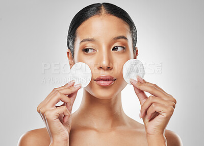 Buy stock photo Studio shot of an attractive young woman using a cotton pad on her face against a grey background