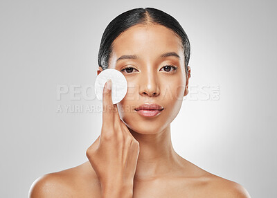 Buy stock photo Studio portrait of an attractive young woman using a cotton pad on her face against a grey background