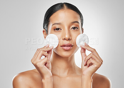 Buy stock photo Studio portrait of an attractive young woman using a cotton pad on her face against a grey background