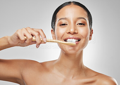 Buy stock photo Studio portrait of an attractive young woman brushing her teeth against a grey background