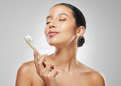 Buy stock photo Studio shot of an attractive young woman brushing her teeth against a grey background