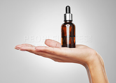 Buy stock photo Studio shot of an unrecognisable woman holding a bottle of serum against a grey background