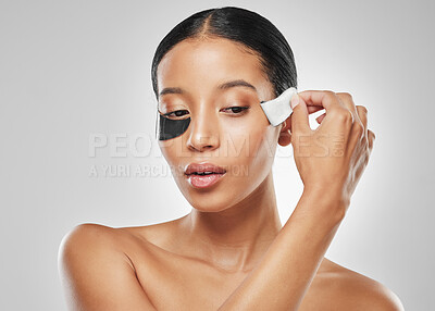 Buy stock photo Studio shot of an attractive young woman removing an under eye patch against a grey background