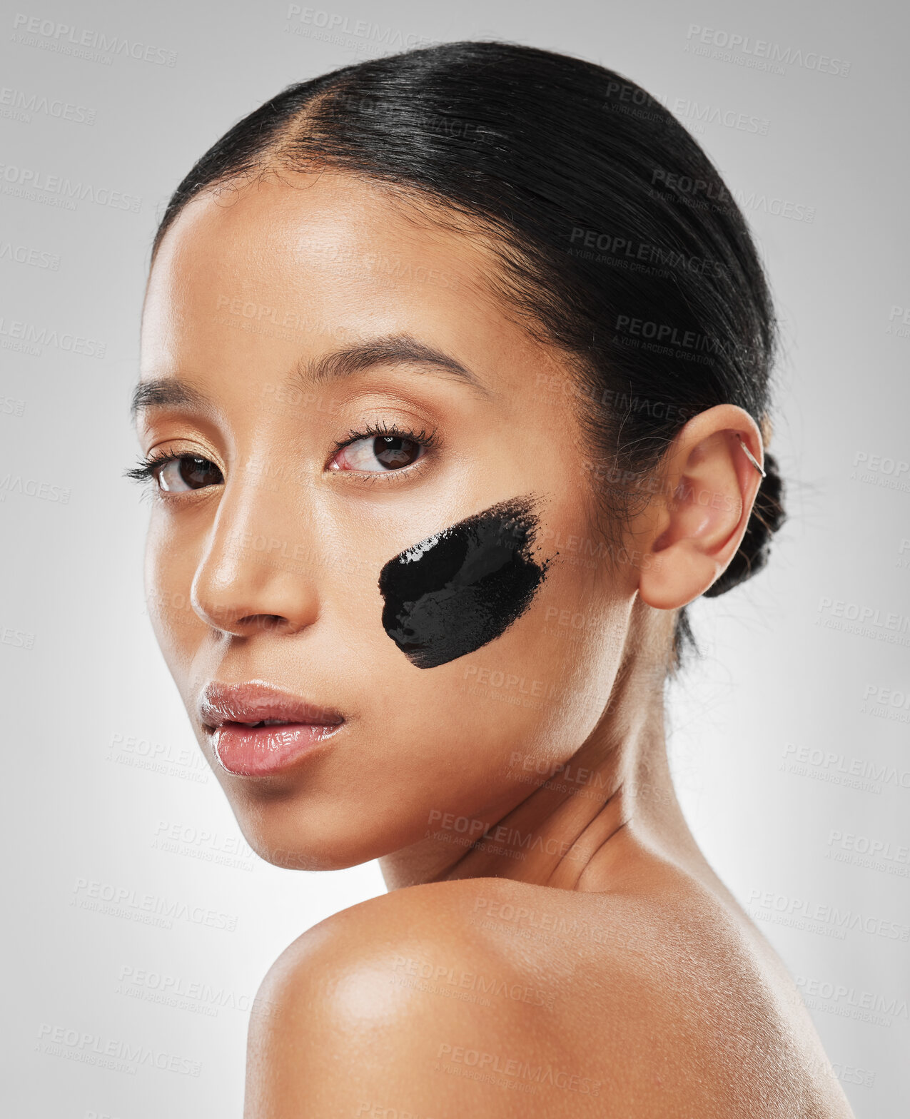 Buy stock photo Studio portrait of an attractive young woman wearing some charcoal face mask against a grey background