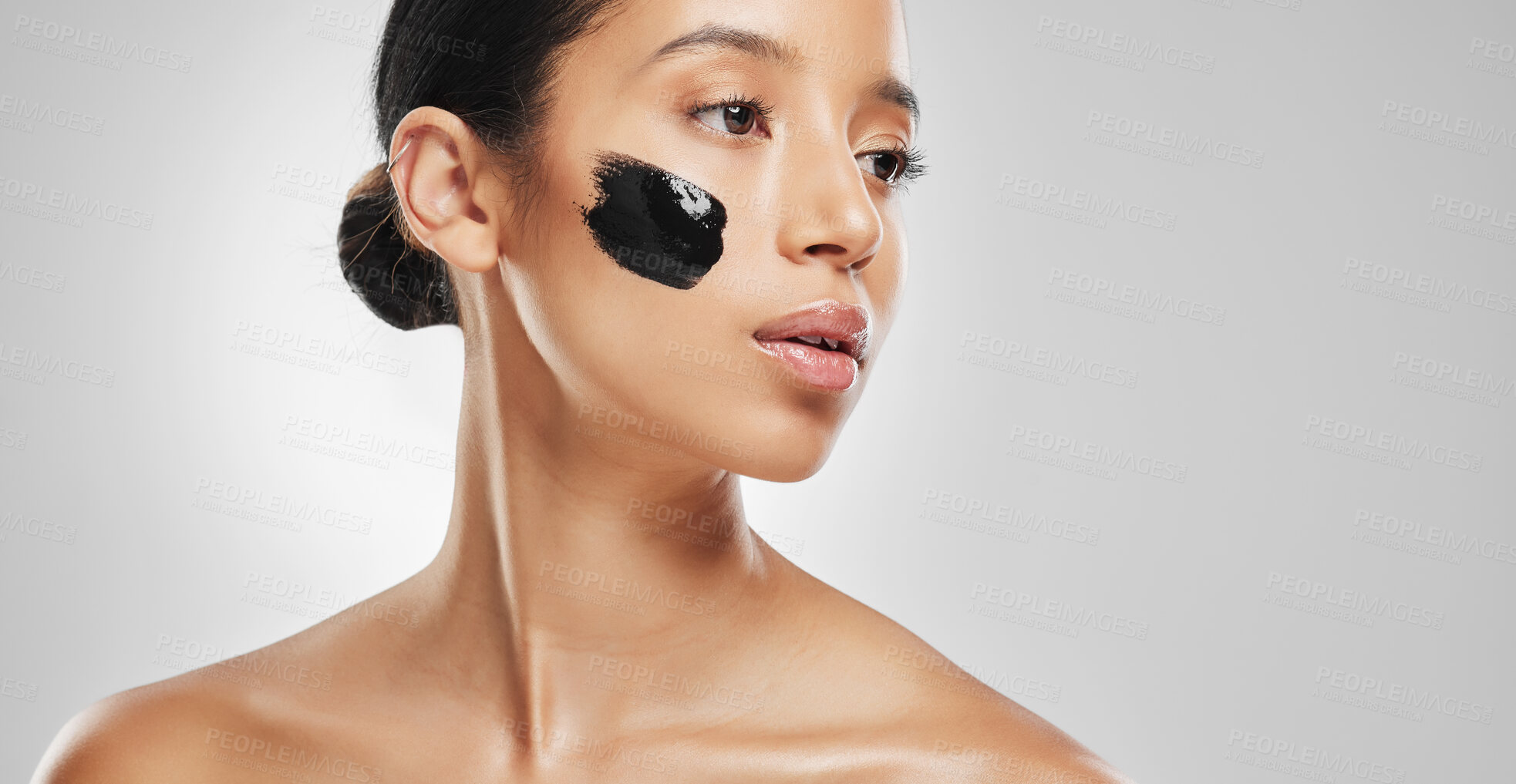 Buy stock photo Studio shot of an attractive young woman wearing some charcoal face mask against a grey background