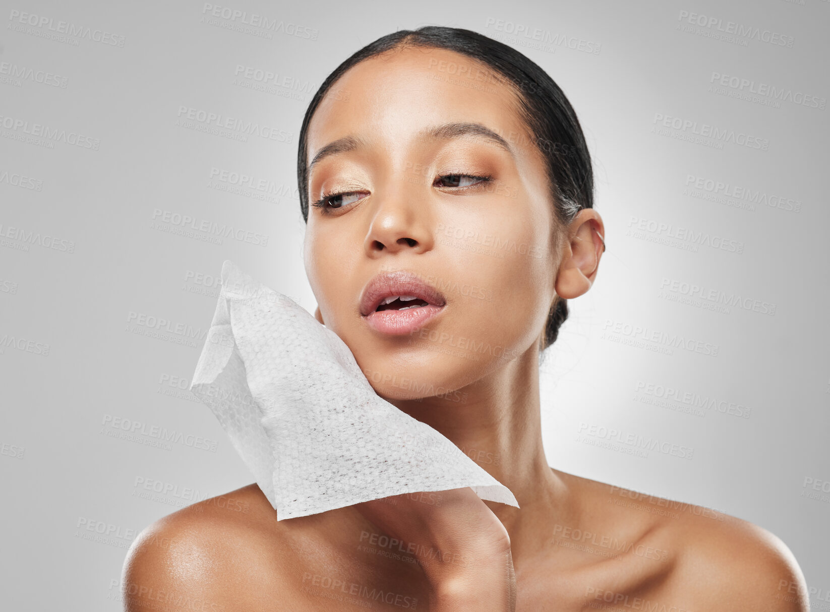 Buy stock photo Studio portrait of an attractive young woman using a facial wipe against a grey background