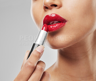 Buy stock photo Studio shot of an unrecognisable woman applying red lipstick against a grey background