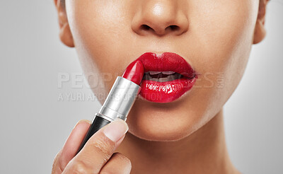 Buy stock photo Studio shot of an unrecognisable woman applying red lipstick against a grey background