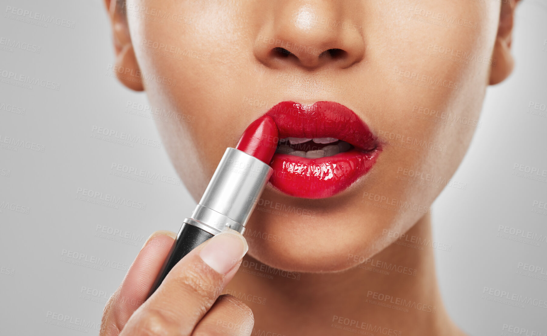 Buy stock photo Studio shot of an unrecognisable woman applying red lipstick against a grey background