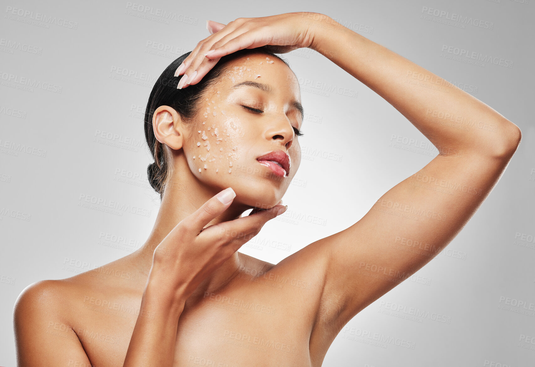 Buy stock photo Studio shot of an attractive young woman posing with sea salt scrub on her face against a grey background