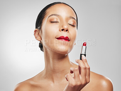 Buy stock photo Studio shot of a young woman applying red lipstick against a grey background