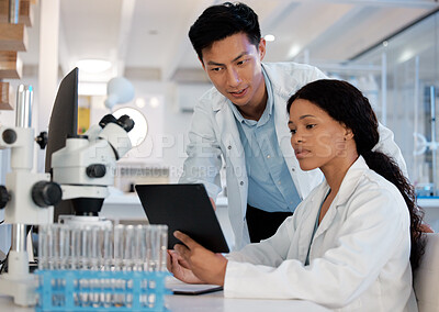 Buy stock photo Shot of two lab techs working together while using a digital tablet