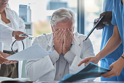 Buy stock photo Shot of a mature male doctor looking overwhelmed at being presented multiple tasks simultaneously by colleagues in the boardroom