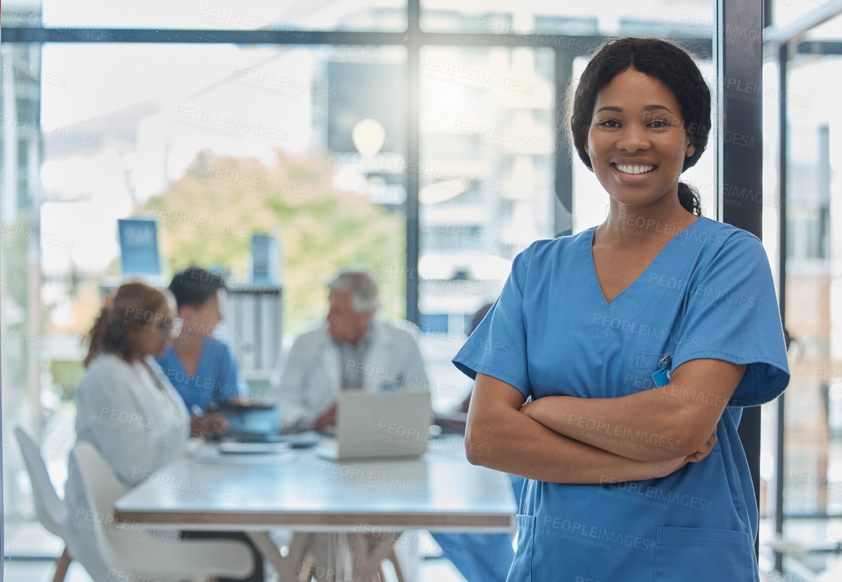 Buy stock photo Cropped portrait of an attractive young female nurse standing in the hospital boardroom while her colleagues meet in the background