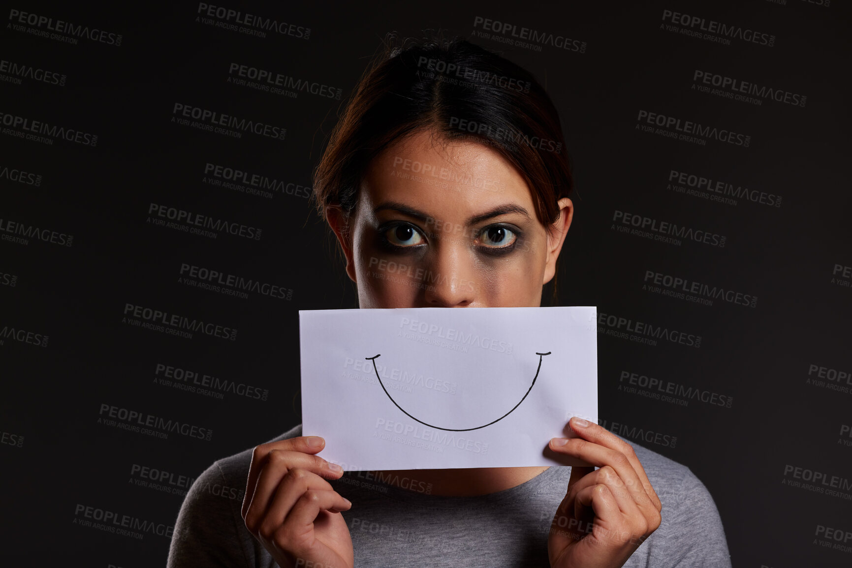 Buy stock photo Sad woman, portrait and abuse with fake smile for trauma or domestic violence in studio on a black background. Female person, victim or young model with paper or masking emotion for hidden expression