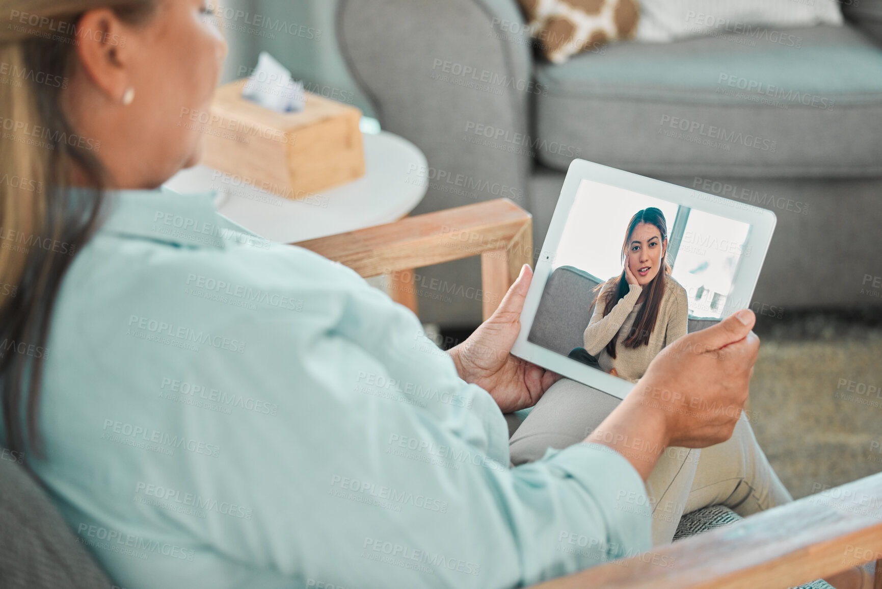 Buy stock photo Shot of a psychologist sitting and using a digital tablet for an online consultation with her patient