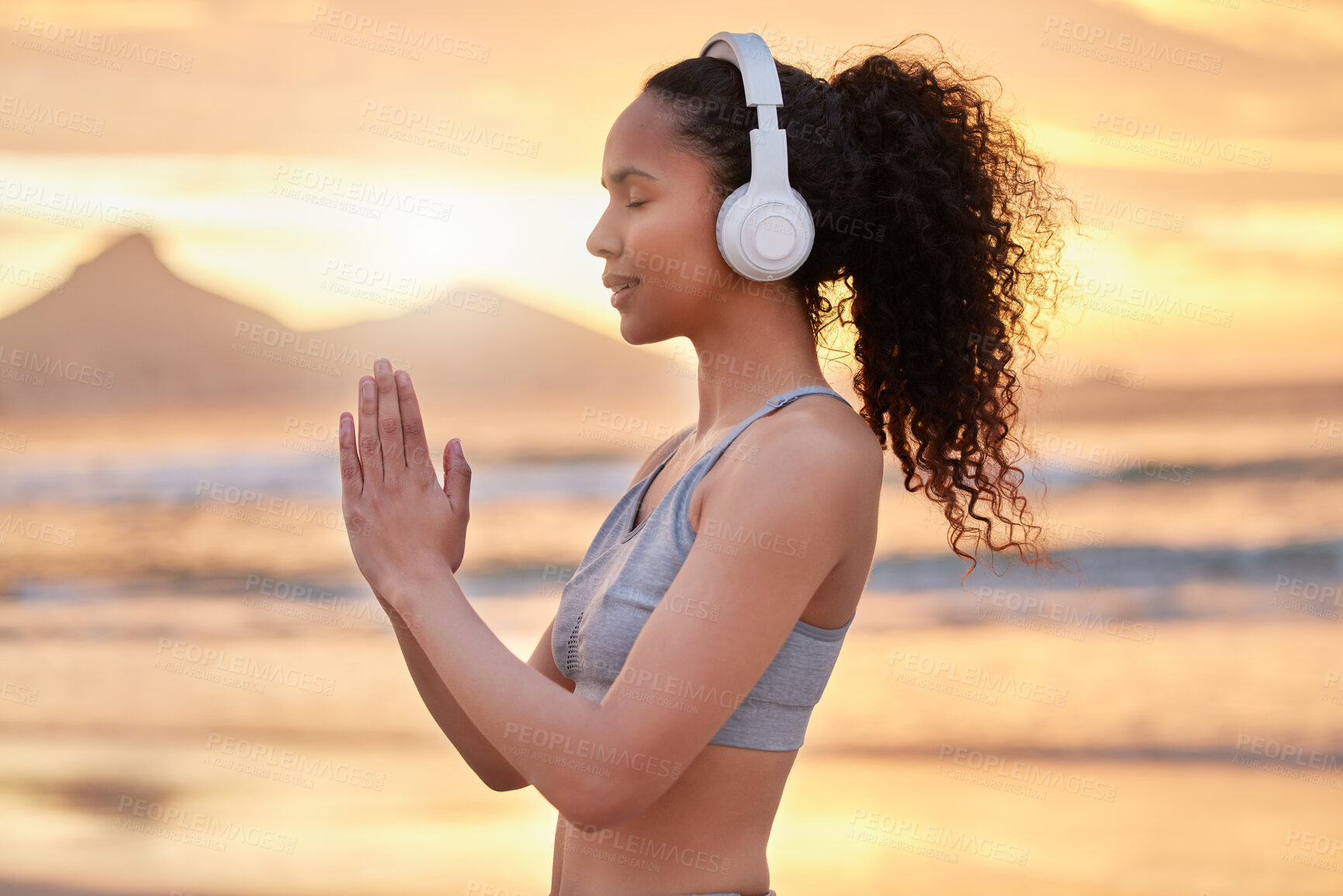 Buy stock photo Woman, yoga and headphones at beach, sunset and profile with smile for music, mindfulness and peace. Person, girl and meditation with namaste, balance and streaming subscription by sea in Colombia