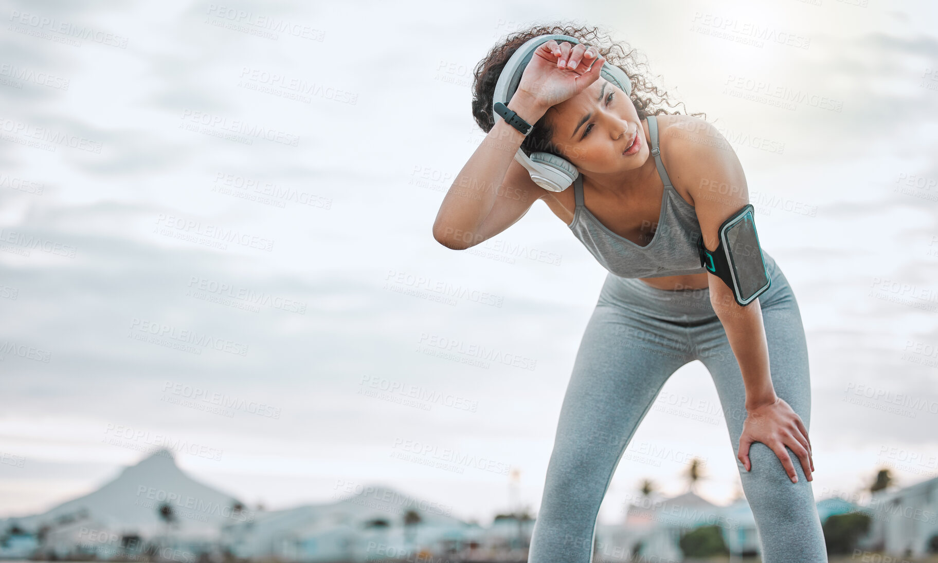 Buy stock photo Fitness, woman and tired runner with headphones outdoor for exercise break, breathing and intense performance. Athlete, person and exhausted of marathon practice with workout run, fatigue and space