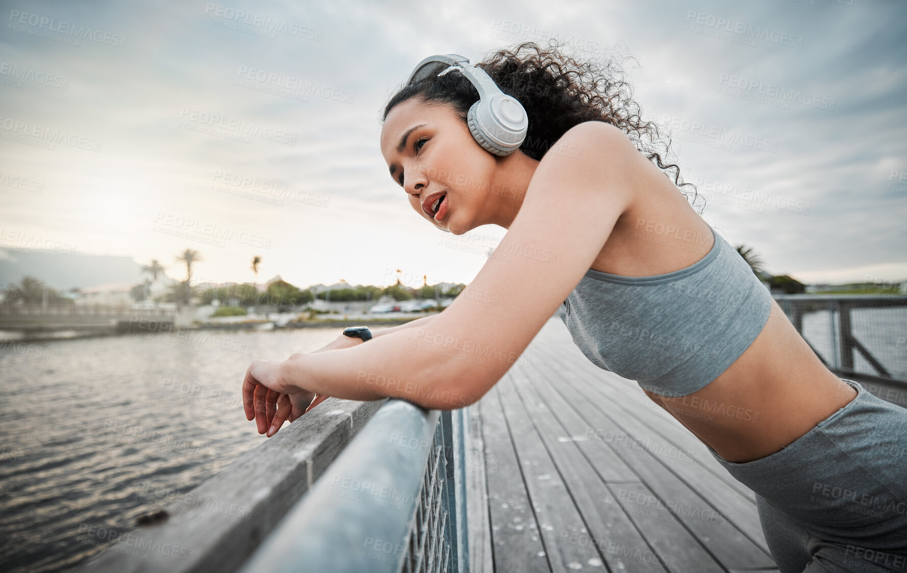 Buy stock photo Outdoor, tired woman and rest with headphones for fitness, hearing music and listening to workout playlist. Female person, runner and break with breathing after running, exercise and audio by bridge