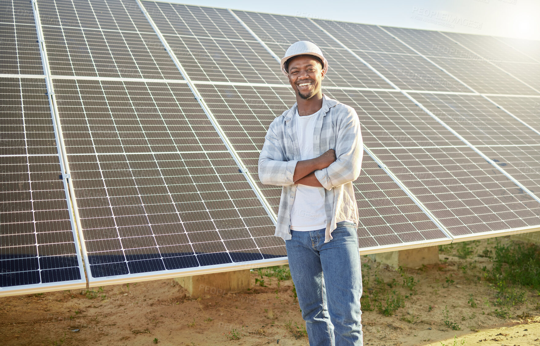 Buy stock photo Shot of a young man standing  in front of solar panel on a farm