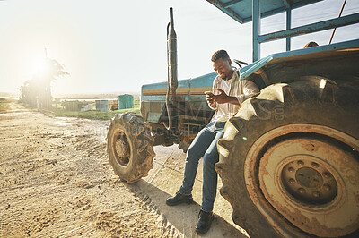 Buy stock photo Shot of a young man using a cellphone while working on a farm