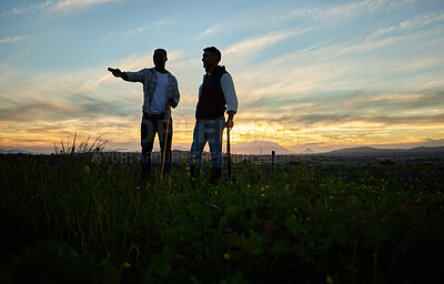 Buy stock photo Shot of two farmers standing on a farm during sunset