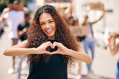 Buy stock photo Shot of a young female protestor forming a heart shape at a protest rally