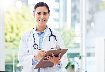 Buy stock photo Portrait of a young doctor writing notes on a clipboard in a hospital