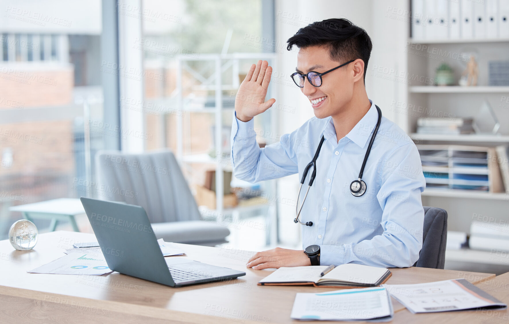 Buy stock photo Medical, video call and telehealth with an asian man doctor in his office at the hospital for remote consulting. Healthcare, virtual and wave with a young male medicine professional working online