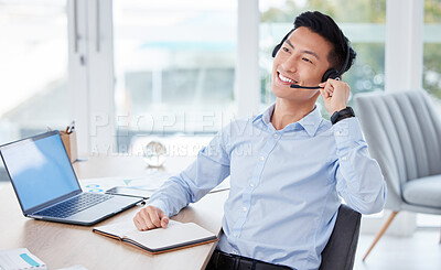 Buy stock photo Shot of a young male call center agent using a laptop and writing in a notebook at work
