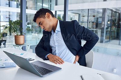 Buy stock photo Shot of a young businessman experiencing back pain while working in an office