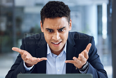 Buy stock photo Shot of a young businessman looking annoyed while working on a laptop in an office
