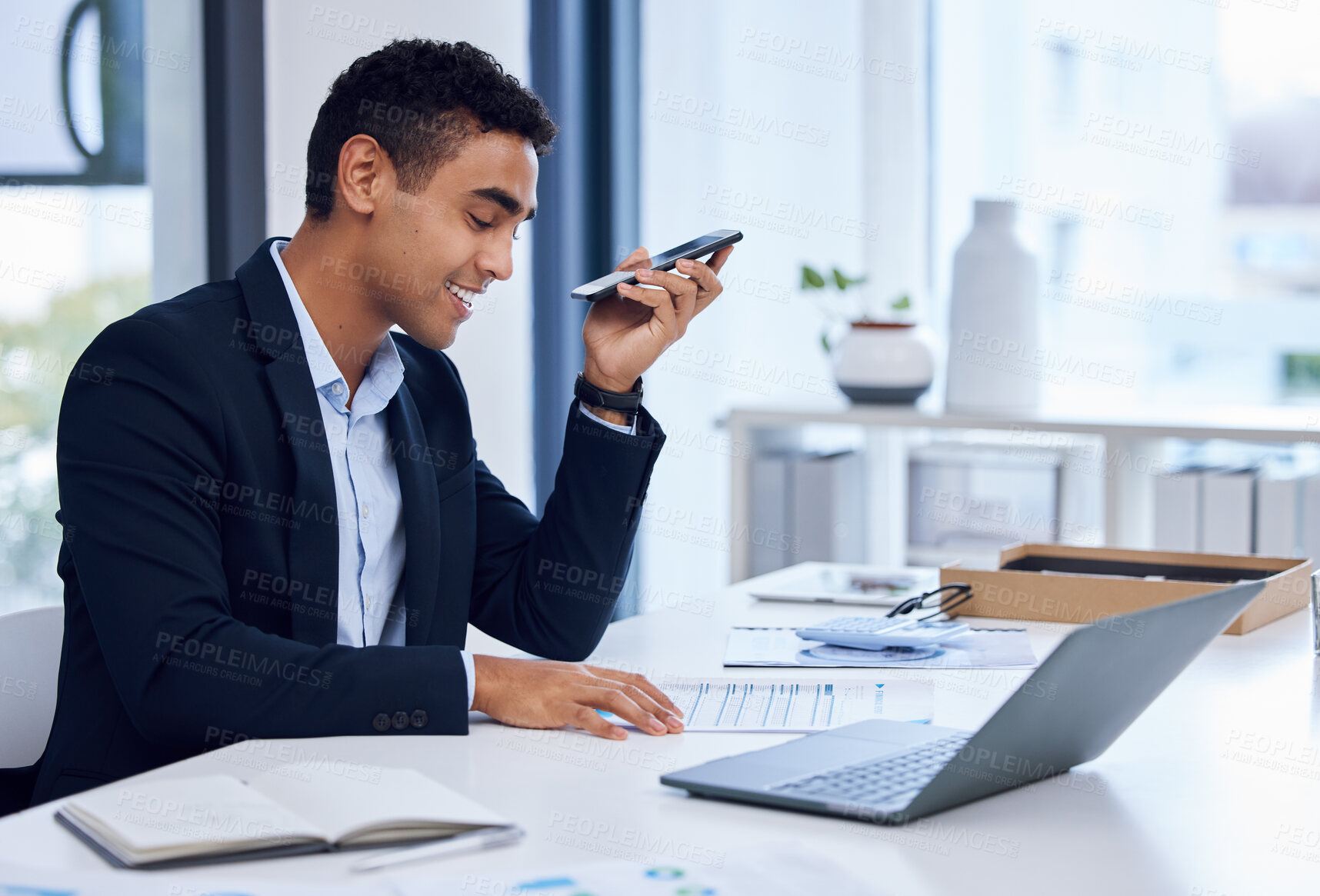 Buy stock photo Shot of a young businessman using a cellphone while going through paperwork in an office