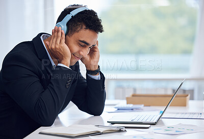 Buy stock photo Shot of a young businessman wearing headphones while working in an office