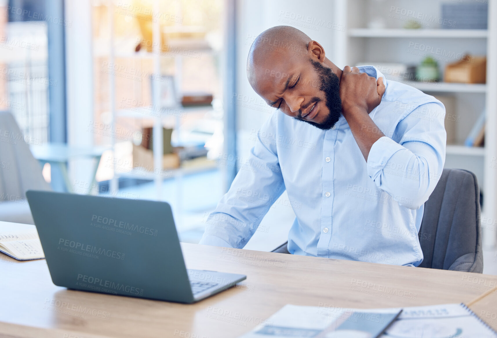 Buy stock photo Shot of a young businessman suffering from back pain in a modern office at work