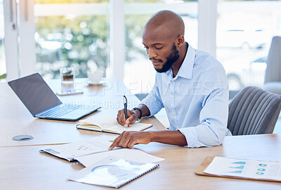 Buy stock photo Shot of a young businessman writing in a notebook at work