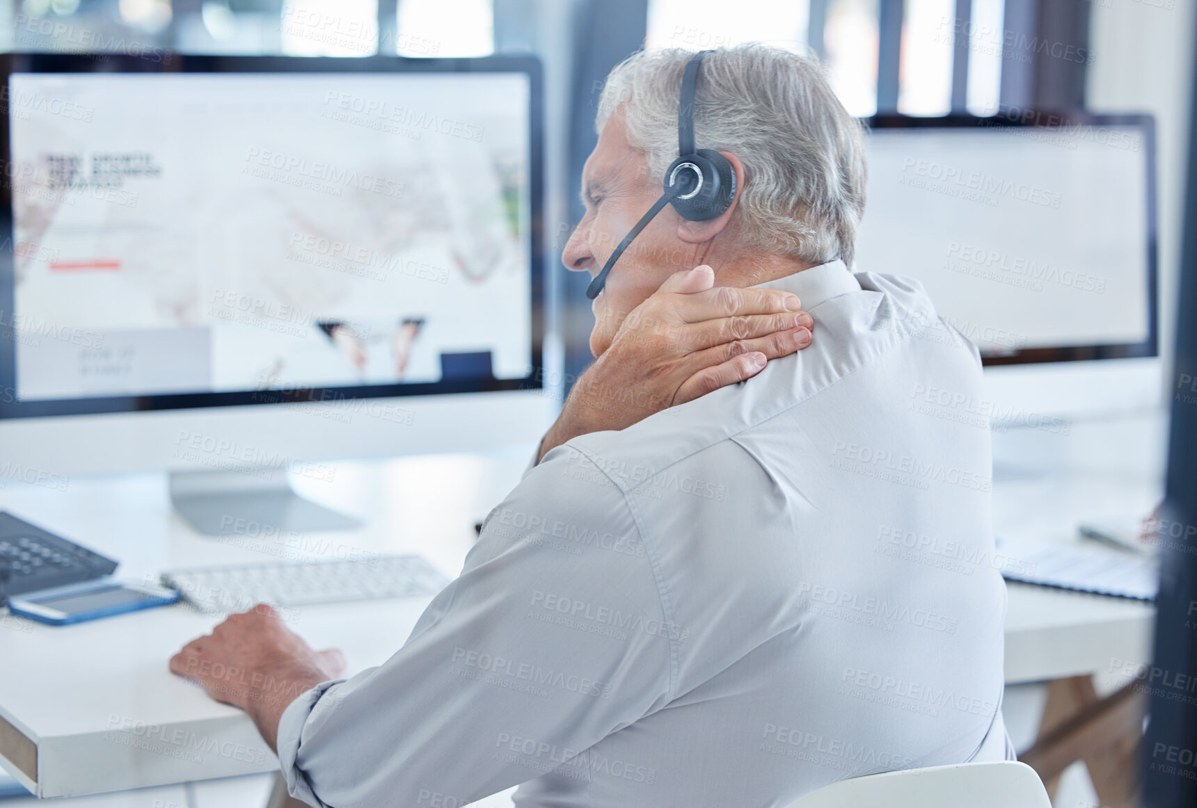 Buy stock photo Shot of a mature call centre agent experiencing neck pain while working in an office