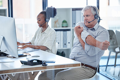 Buy stock photo Shot of a mature call centre agent stretching his arms while working in an office