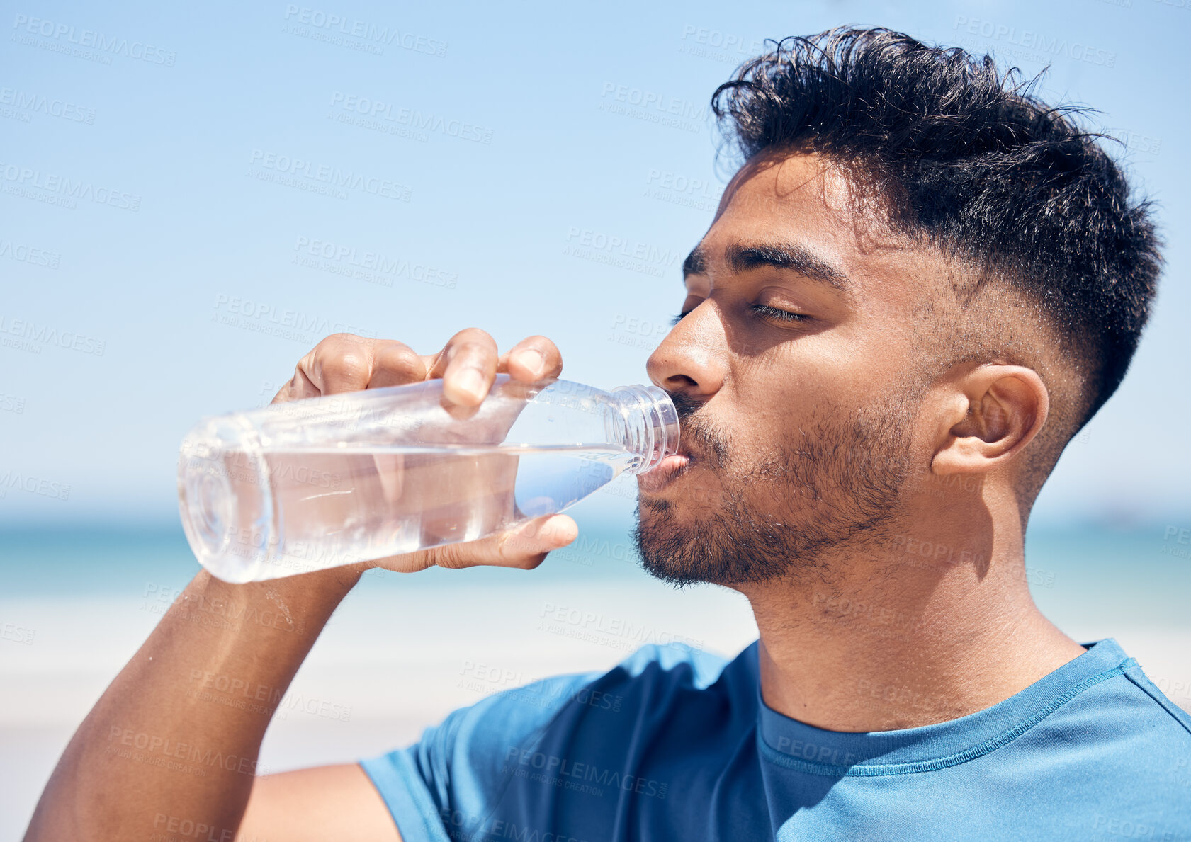 Buy stock photo Break, fitness and drinking water with runner man on beach for cardio training, marathon or workout. Exercise, hydration and recovery with thirsty sports athlete outdoor on coast for health routine