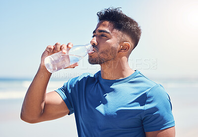 Buy stock photo Shot of a man drinking water while out for a run on the beach