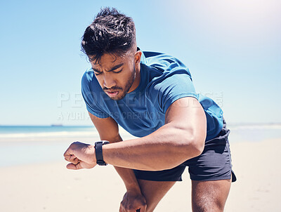 Buy stock photo Shot of a man checking his watch during a workout on the beach