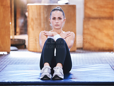 Buy stock photo Portrait of a sporty young woman doing sit ups while exercising in a gym
