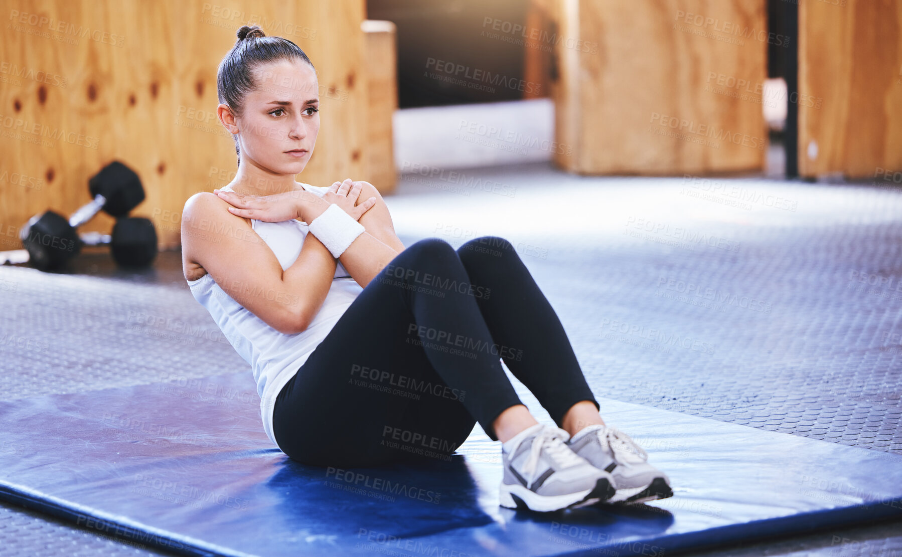 Buy stock photo Shot of a sporty young woman doing sit ups while exercising in a gym