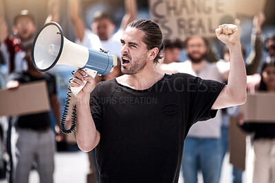 Buy stock photo Shot of a young man yelling through a megaphone during a protest