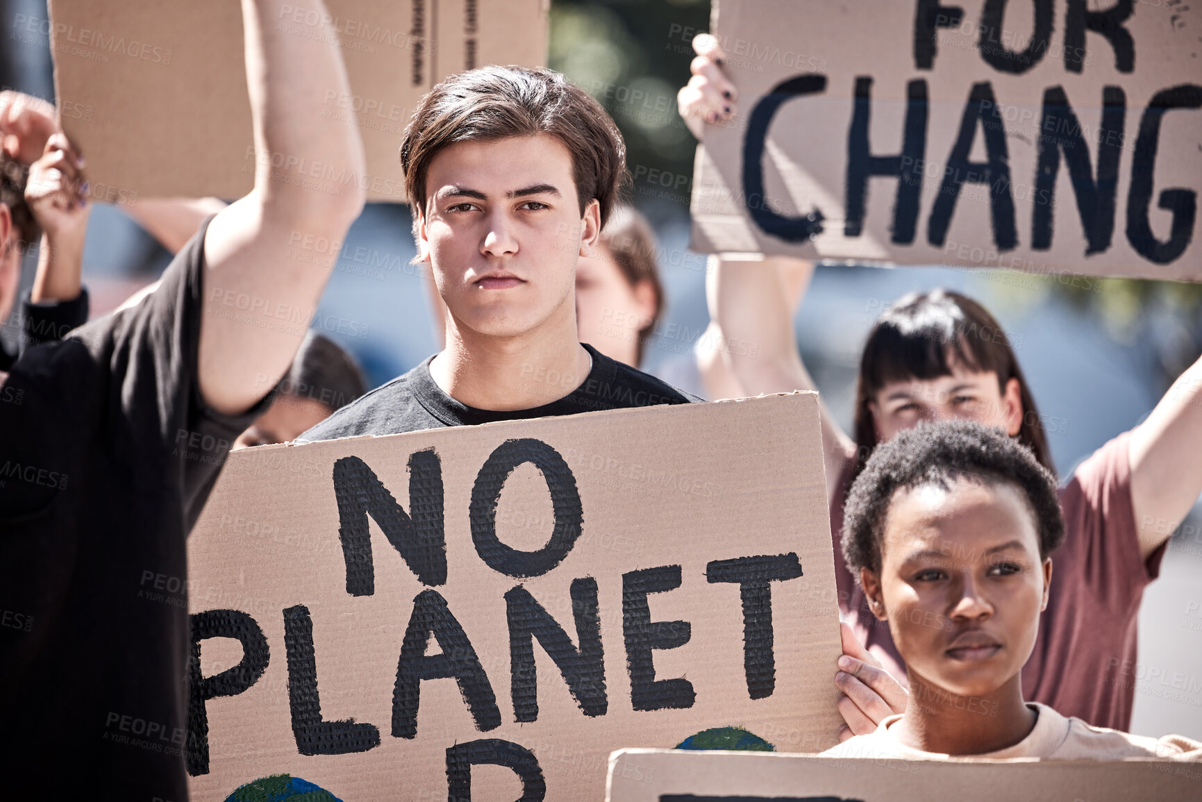 Buy stock photo Shot of a group of young people during a protest rally holding placards
