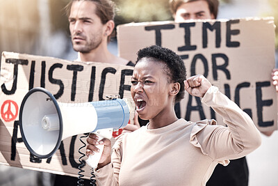 Buy stock photo Shot of a young woman shouting through a megaphone at a protest
