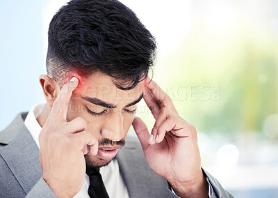 Buy stock photo Shot of a young businessman experiencing a headache while working in an office