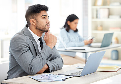 Buy stock photo Shot of a young businessman looking thoughtful while working on a laptop in an office