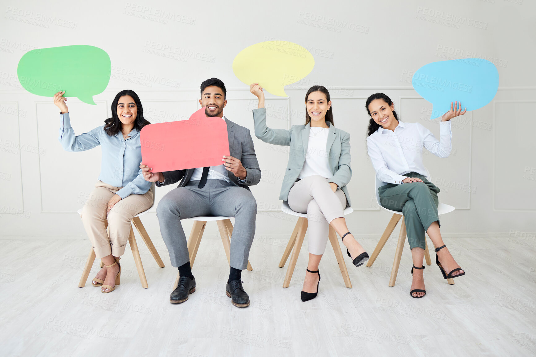 Buy stock photo Portrait of a group of businesspeople holding speech bubbles while sitting in line against a grey background